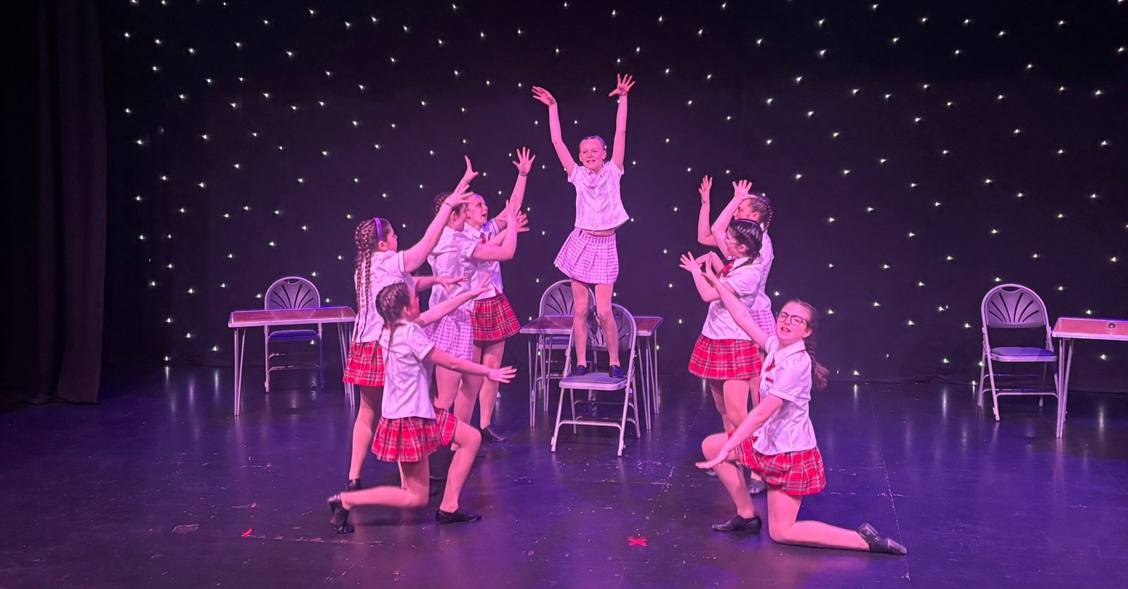 Tap dance students performing synchronized routine on stage
